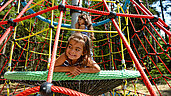 Mädchen spielt im Kletterturm auf dem Waldspielplatz des Familienhotels Ulrichshof im Bayerischen Wald.