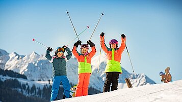 Drei glückliche Kinder auf der Skipiste na des Familienhotels Hotel Spa- & Familien-Resort Krone im Allgäu.