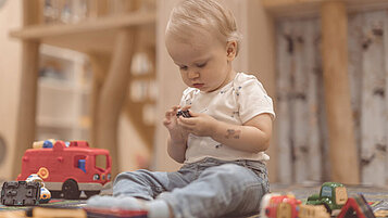Kleinkind sitzt im Happy-Club des Familienhotels Gorfion und spielt mit Spielsachen