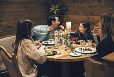 Die ganze Familie sitzt entspannt zum Abendessen im Familienhotel Post Family Resort im Salzburger Land.
