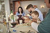 Familie sitzt am gedeckten Tisch im Restaurant des Familienhotels Amiamo im Salzburger Land und isst ihr Abendessen