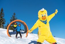 Kinder fahren auf Skiern durch einen Tunnel im Winter-Familienurlaub in Kärnten