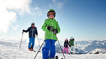 Junge steht auf Skiern auf der Piste im familienfreundlichen Skigebiet im Salzburger Land.