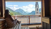 Frau in der Sauna des Kinderhotels Stefan in Österreich. Von der Sauna hat man einen schönen Panoramablick in die umliegende Berglandschaft.