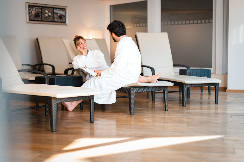 Eltern entspannen auf den Ruheliegen im Wellnessbereich des Familienhotels Das Hopfgarten