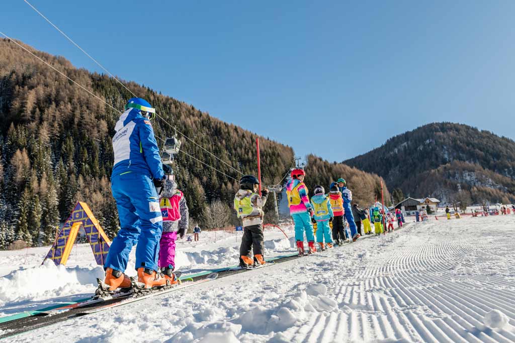 Kinder beim Skifahren in der Skischule im Familienhotel Huber in Südtirol.