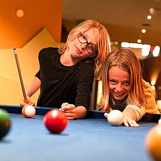 Teenager beim Billard spielen im Familienurlaub