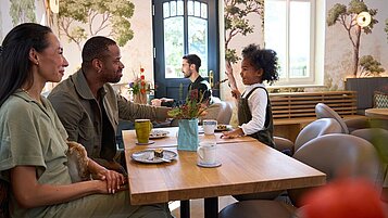 Eine Familie sitzt in der "Plauderei" im Landhaus Averbeck gemütlich zusammen bei Kaffee und Kuchen.