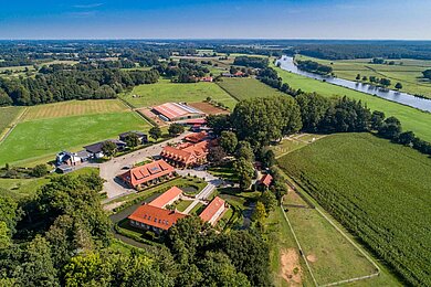 Außenansicht des Familienhotels Gut Landegge im Sommer von oben. Das Hotel ist umgeben von Natur, Wald und Wiesen.