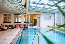 Heller Indoor-Pool mit Relaxliegen und Sitzsäcken im Familienhotel Bruckwirt für entspannte Stunden am Wasser.