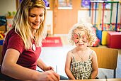 Ein Kind mit einer Kinderbetreuerin beim Kinderschminken im Landgut Furtherwirt in Tirol ab.