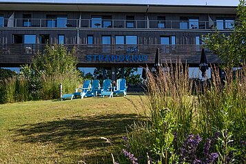 Außenansicht vom Familienhotel Strandkind an der Ostsee mit Liegestühlen auf der Wiese