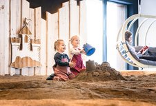 Zwei Mädchen spielen in der Indoor Sandkiste des Familienhotels Allgäuer Berghof.