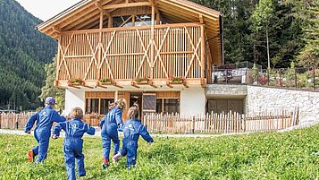 Kinder toben in der Wiese auf dem Gelände des Familienhotels Huber in Südtirol