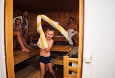 Junge wedelt mit einem Handtuch in der Luft in der Familiensauna des Familienhotels Kirchheimerhof in Kärnten.