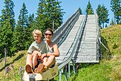 Mutter und Tochter fahren gemeinsam auf einer Sommerrodelbahn in Kärnten