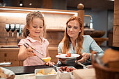 Mutter und Tochter bedienen sich am Buffet des Familienhotels Family Home Alpenhof.