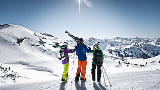 Eine Gruppe von Leuten machen Pause, halten ihre Ski und genießen die Aussicht im Winter vom Nebelhorn im Allgäu. Der Tag ist strahlend schön.