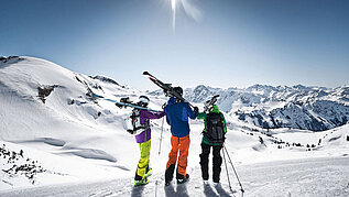 Eine Gruppe von Leuten machen Pause, halten ihre Ski und genießen die Aussicht im Winter vom Nebelhorn im Allgäu. Der Tag ist strahlend schön.