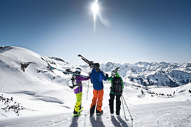 Eine Gruppe von Leuten machen Pause, halten ihre Ski und genießen die Aussicht im Winter vom Nebelhorn im Allgäu. Der Tag ist strahlend schön.