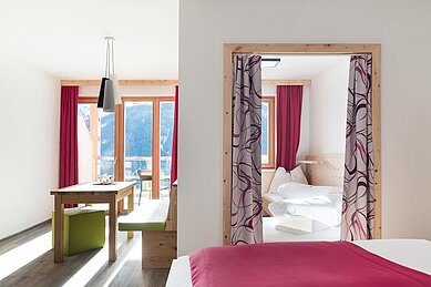 Familiensuite mit Balkon und Panoramafenstern mit einem wunderschönen Blick auf die Berge im Familienhotel Almfamilyhotel Scherer in Tirol.