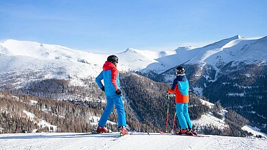 Zwei Kinder stehen auf Skiern auf der Skipiste in Kärnten.