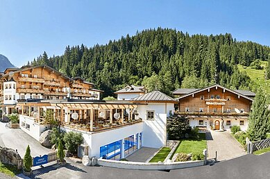 Außenansicht des Habachklause Familien Bauernhof Resort im Salzburger Land, umgeben grünen Wäldern im Sommer.