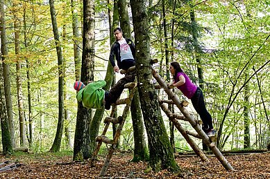 Eltern beim Ausführen von Fitnessübungen im Abenteuerwald am Landhaus zur Ohe im bayerischen Wald.