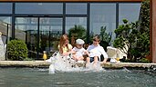 Drei Kinder sitzen am Beckenrand des Pools des Familienhotels Ulrichshof und lassen ihre Füße ins Wasser hängen.