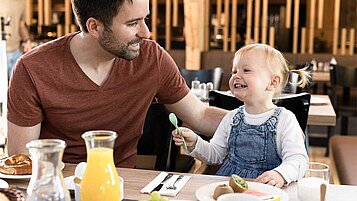 Papa und Kind beim Frühstück im Familienhotel.