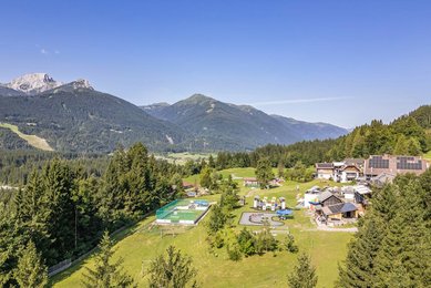 Weitläufige Hotelanlage des Familienhotels Ramsi mit Spielplatz, Sportbereich und herrlichem Bergpanorama in Kärnten.