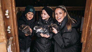 Zwei Kinder halten jeweils ein Meerschweinchen in der Hand und streicheln es. 