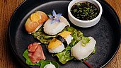 Ein fein angerichteter Teller mit einer Auswahl an Maki-Sushi, garniert mit frischen Blumen und Blättern, serviert mit einer Schale Sojasauce im Hotel Habachklause.