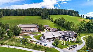 Außenansicht des Familienhotels Der Ponyhof in der Steiermark. Das Hotel ist umgeben von einem großzügigen Außenbereich mit viel Platz für die Kinder zum Spielen.