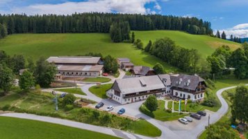 Außenansicht des Familienhotels Der Ponyhof in der Steiermark. Das Hotel ist umgeben von einem großzügigen Außenbereich mit viel Platz für die Kinder zum Spielen.