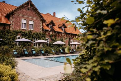 Der gepflegte Außenpool des Familienhotels Landhaus Averbeck mit Sonnenliegen und Sonnenschirmen lädt zum Entspannen im Garten ein.