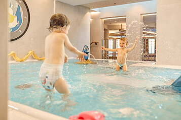 Zwei Kleinkinder planschen im Babybecken des Alpenhotels Kindl in Tirol.