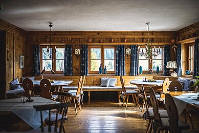 Gemütliche Stube im traditionellen alpenländischen Stil mit Holztäfelung, rustikalen Möbeln und einem Kronleuchter, mit Panoramablick auf die Berge.