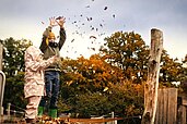 Zwei Kinder spielen mit dem Laub auf dem Außenspielplatz des Familienhotels Landhaus Averbeck in der Lüneburger Heide.