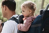 Vater wandert mit seinem Kleinkind in der Kraxe durch die Natur rund ums Familienhotel Tirolerhof