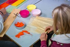 Kinder basteln mit buntem Papier und Scheren in der kreativen Kinderbetreuung des Familienhotels Bruckwirt.