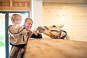 Mutter und Kind sind im Aktiv vom Familienhotel Landhaus zur Ohe und streicheln das Pferd.