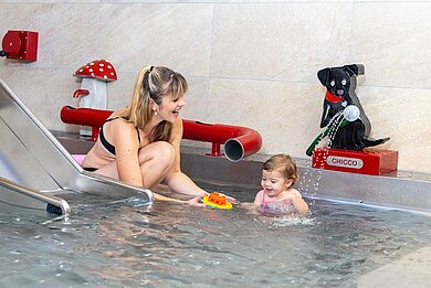 Mutter spielt mit Ihrer Tochter im Kinderschwimmbecken des Familienhotels Feldberger Hof im Schwarzwald.