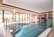 Moderner Indoor-Pool mit großen Panoramafenstern und Relaxliegen im Familienhotel Oberkarteis.