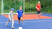 Zwei Jungs spielen mit ihrem Vater gemeinsam Fußball im Familienurlaub im Family Club Harz