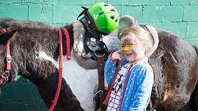 Kleines Kind streichelt ein Ponny im Familienhotel Borchards Rookhus.