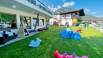 Große Spielwiese mit Kletterstein, Tracktoren und Fußballtor im Wellness- & Familienhotel Egger in Saalbach Hinterglemm.