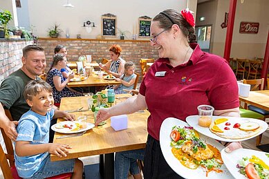 Familie wird im Restaurant des Familienhotels Family Club Harz von einer freundlichen Bedienung bedient.