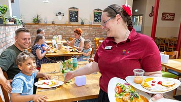 Familie wird im Restaurant des Familienhotels Family Club Harz von einer freundlichen Bedienung bedient.