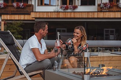 Eltern lassen den Abend bei einem Drink auf der Terrasse des Familienhotels Huber in Südtirol ausklingen.